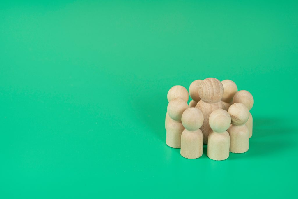 Showing customer engagement and retention via wooden blocks shaped like people huddling together